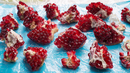 pieces of broken pomegranate scattered on the wet blue polyethylene surface