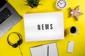 News word on lightbox on modern yellow office desktop with laptop, smartphone, coffee mug, notebook. world imbued with information, informational reasons, daily news, messages, informational noise