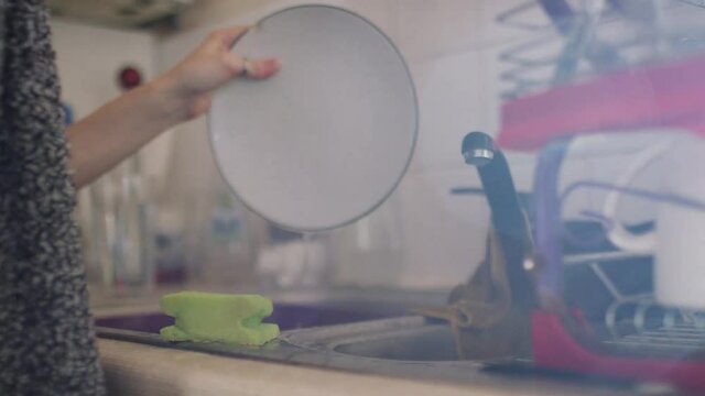 Hands of a woman at the kitchen sink washing up