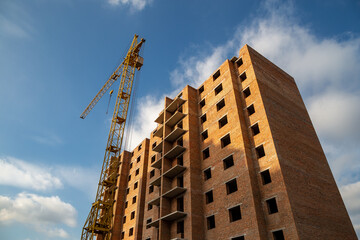 Fototapeta premium Work in progress on a new apartment block. Tall building under construction with cranes. Construction Site of New Building.