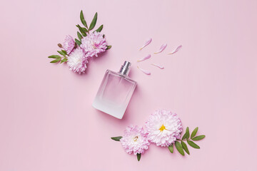 A bottle of perfume, flowers and petals on pink background.