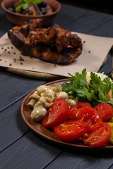 Food set with grilled pork ribs, pickled vegetables, bacon, salad, and moonshine  on black wooden background