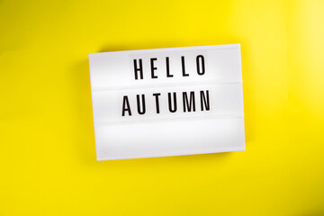 Hello Autumn message on lightbox on yellow background isolated. Top view, flat lay Autumn season, positive mood, harvest time, leaffall, fall concept