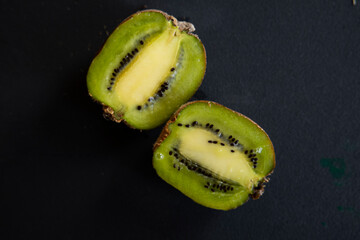 half a fresh kiwi in water on a black background with air bubbles