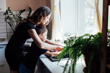 Mom with son wash vegetables in the kitchen
