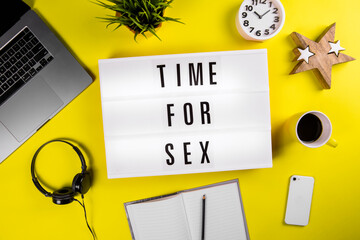 Time For Sex message on lightbox on modern yellow office desktop with laptop, smartphone, alarm clock at 10.10 pm, coffee mug, notebook. couple have special time together by having sex or make love