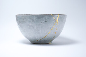 Kintsugi Japanese grey bowl. Gold cracks restoration on pottery restored with the antique Kintsugi...