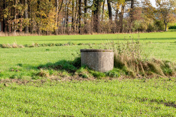 Auf einem Feld steht ein Brunnen. Die Brunnenringe aus Beton sind tief in die Erde eingelassen um an das Grundwasser zu kommen.