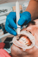 Dental practice, the dentist removes stones and hard plaque from the teeth with the help of...