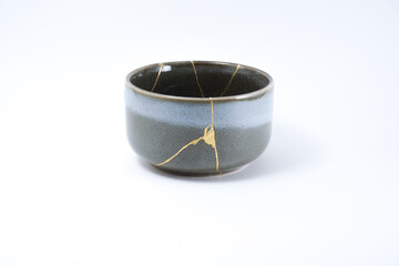 Kintsugi Japanese grey bowl. Gold cracks restoration on pottery restored with the antique Kintsugi restoration technique. The beauty of imperfections. representation of trauma. 