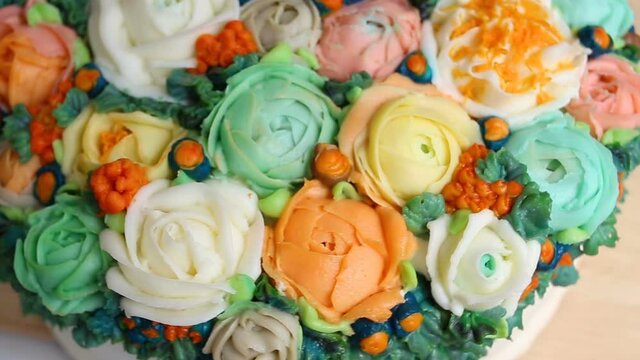 The cake is decorated with realistic edible cream flowers of roses, Ranunculus, peonies and Rubus chamaemorus, extreme close-up, high angle, real time, pastry Floristics, the object rotates in the fra