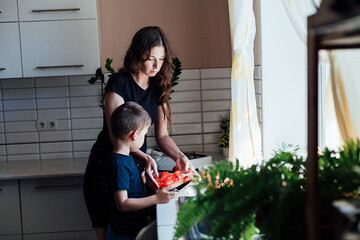 Mom and young son cut vegetables for salad in the kitchen