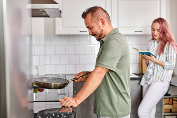 man prepare breakfast, couple at home at weekend, beautiful couple in the light modern kitchen, enjoying spending time together