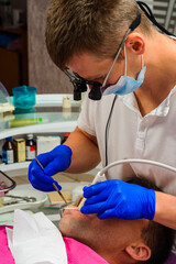 Dental clinic, private practice, the dentist uses binoculars for the best result and work, the...