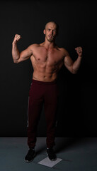 Fototapeta na wymiar A sports guy of beautiful strength builds muscles in training. Strong bodybuilder, strong abs, shoulders, biceps, tempus and pronator.