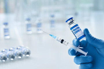 Male doctor hand wears medical glove holding syringe and vial bottle with covid 19 corona virus...