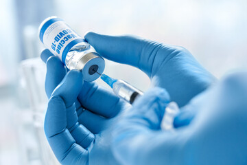 Male doctor hand wears medical glove holding syringe taking covid 19 corona virus liquid vaccine...