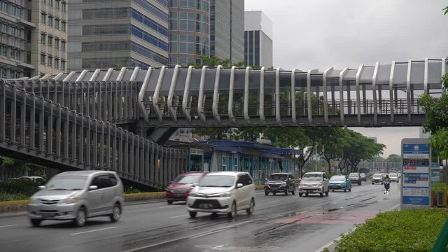rainy day jakarta city downtown famous pedestrian bridge traffic street slow motion panorama 4k indonesia
