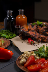 Fried ribs with pepper and bottle of wine on black wooden background