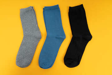 Pair of sock for clothing on yellow background. Set of long socks gray, blue and black,