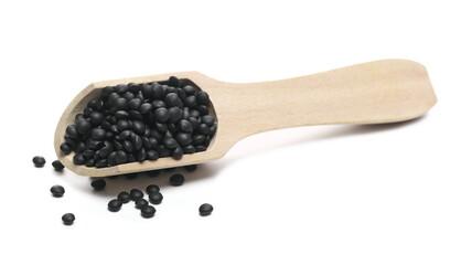 Black beluga lentils in wooden spoon isolated on white background