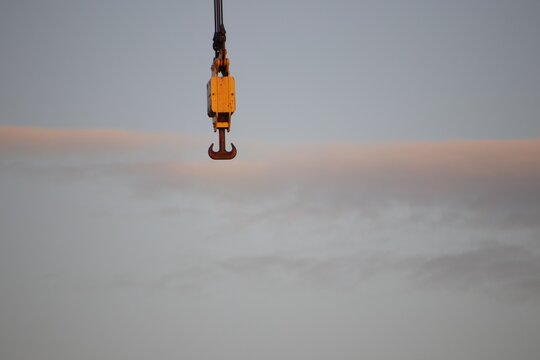 Low Angle View Of Crane Hook Hanging Against Sky At Sunset