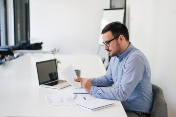 Stressed out businessman in office making important decision about serious problem working under pressure and tight deadline looking at spreadsheet document report account solving bad situation