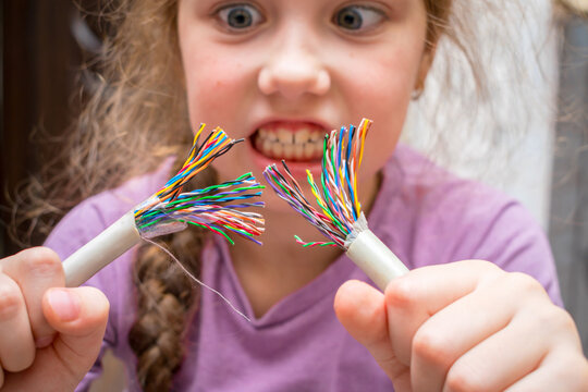 Breakage of colored wires. Little girl tears the communication internet cable with her hands. Damage to the copper telephone cable. Selective focus