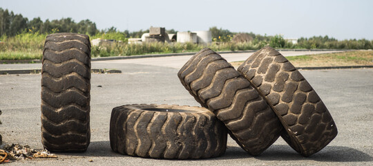 Close-up of dusty tires on asphalt. Green trees on background. Summer day.