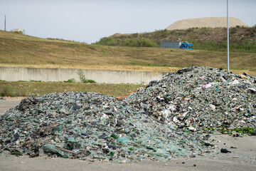 Dump of broken glass and mirrors. Two heaps. Summer day. Hills on background.