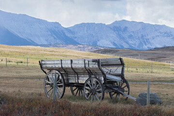 Fototapeta na wymiar Old and decaying farming wagon sits alone in a field on the eastern edge of the Rocky Mountains in rural Alberta