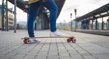 Obraz premium Close up of the foot on a guy on a skateboard, at the train station, waiting for the train.