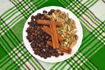 Coffee, cardamom, cinnamon on a white plate. Checkered towel.