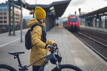 A man in winter clothes, waiting with his bike, the train. In the background the train that is...