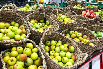 ripe green and yellow apples lie in round baskets in grocery store ready for sale. Vitamin food for healthy eating.