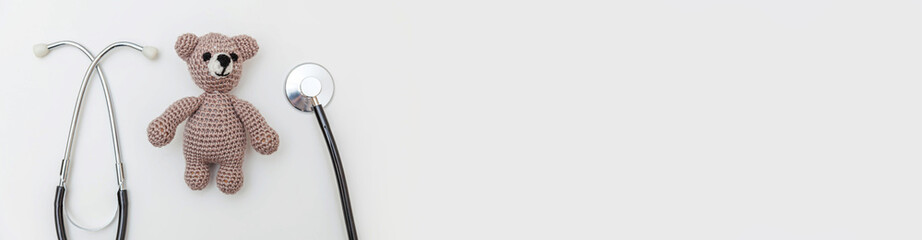 Simply minimal design toy bear and medicine equipment stethoscope isolated on white background. Health care children doctor concept. Pediatrician symbol. Flat lay top view copy space. Banner © Юлия Завалишина