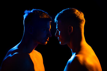 Silhouette of two men standing each other in profile, concept of conflict, rivalry and screaming.