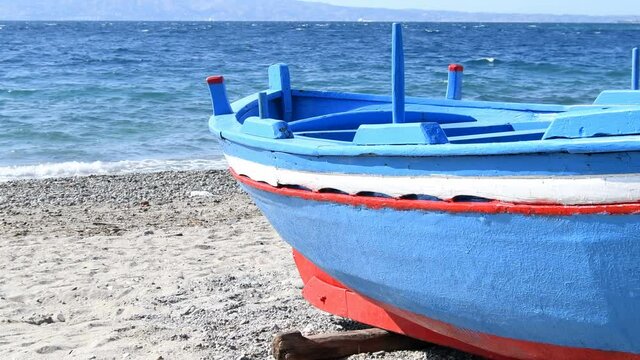 Red&nbsp;and&nbsp;white&nbsp;blue&nbsp;hull&nbsp;of&nbsp;a&nbsp;fisherman's&nbsp;boat&nbsp;from&nbsp;southern&nbsp;Italy&nbsp;on&nbsp;the&nbsp;beach&nbsp;on&nbsp;a&nbsp;day&nbsp;of&nbsp;strong&nbsp;wind&nbsp;and&nbsp;slightly&nbsp;choppy&nbsp;sea - Real Time 4K
