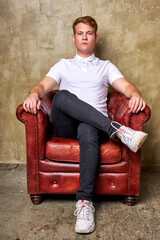 portrait of bossy caucasian man on leather chair sofa or couch, sit looking at camera, posing.