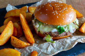 hamburger on a slate board with wedges fries