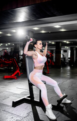 Obraz na płótnie Canvas A girl in sportswear in a professional gym works out with fitness equipment. Healthy lifestyle concept