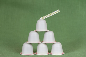 Close-up of compostable coffee capsules, on a green background. There is an inscription on them...