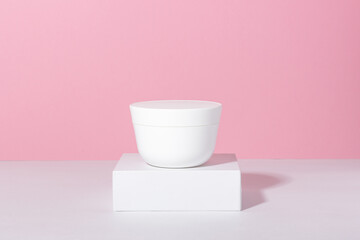 Natural cosmetic. Jar with cream or face mask. White container with women's skin care product on the podium.