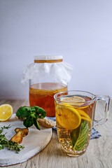 Homemade fermented raw kombucha tea in a in a glass jar  with different flavorings- lemon, ginger, mint, thyme. Healthy natural probiotic flavored drink. Copy space