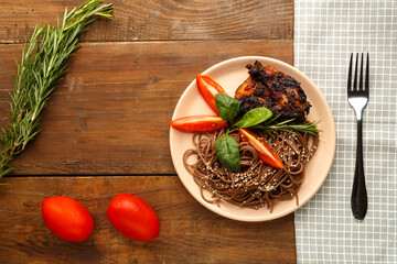 Beige plate soba with chicken tomatoes and spinach on a linen napkin with a fork, greens and tomatoes on the table.