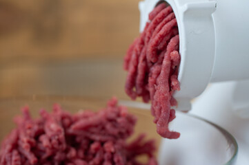Cook makes minced fresh meat in a meat grinder