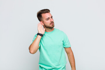young man looking serious and curious, listening, trying to hear a secret conversation or gossip,...