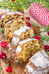 Christmas stollen with icing sugar, marzipan and raisins. Traditional Dresden christ pastry. On table background with fir tree branches and Christmas decoratioon top view copy space