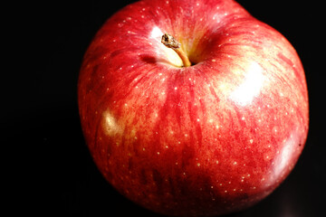 Red Apple on a black background. Half-light and a brightly lit Apple.
