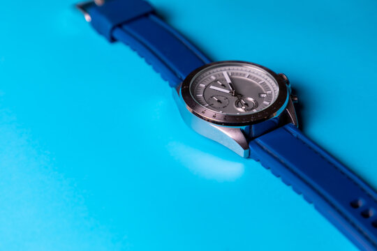 Reloj de pulsera plateado con correa azul sobre fondo azul cielo, con espacio para texto. Accesorios para hombre.